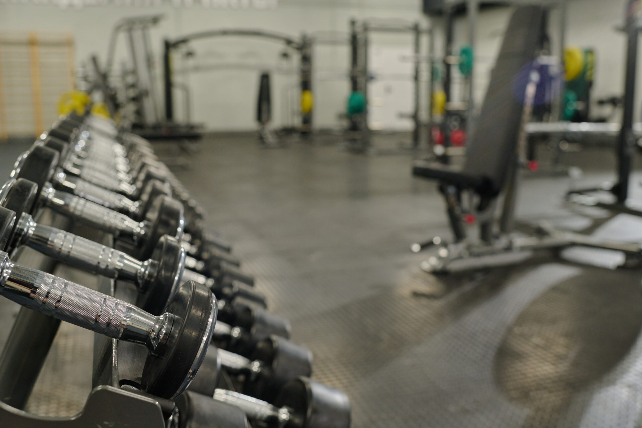 Medium close up of metal rack with metal dumbbells in empty workout zone